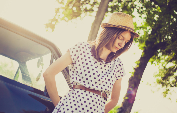 Retro style young woman standing next to the car