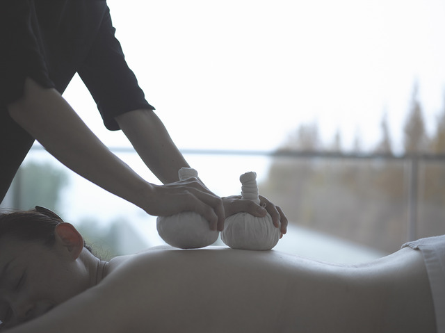 ドライハーブを包んだハーブボールを押しあてて身体をほぐしていく